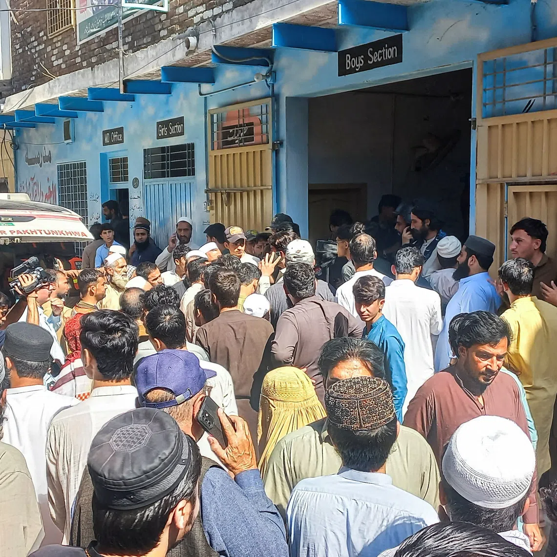 Residents and rescue workers gather near an ambulance after a school roof collapse in Peshawar, Pakistan.