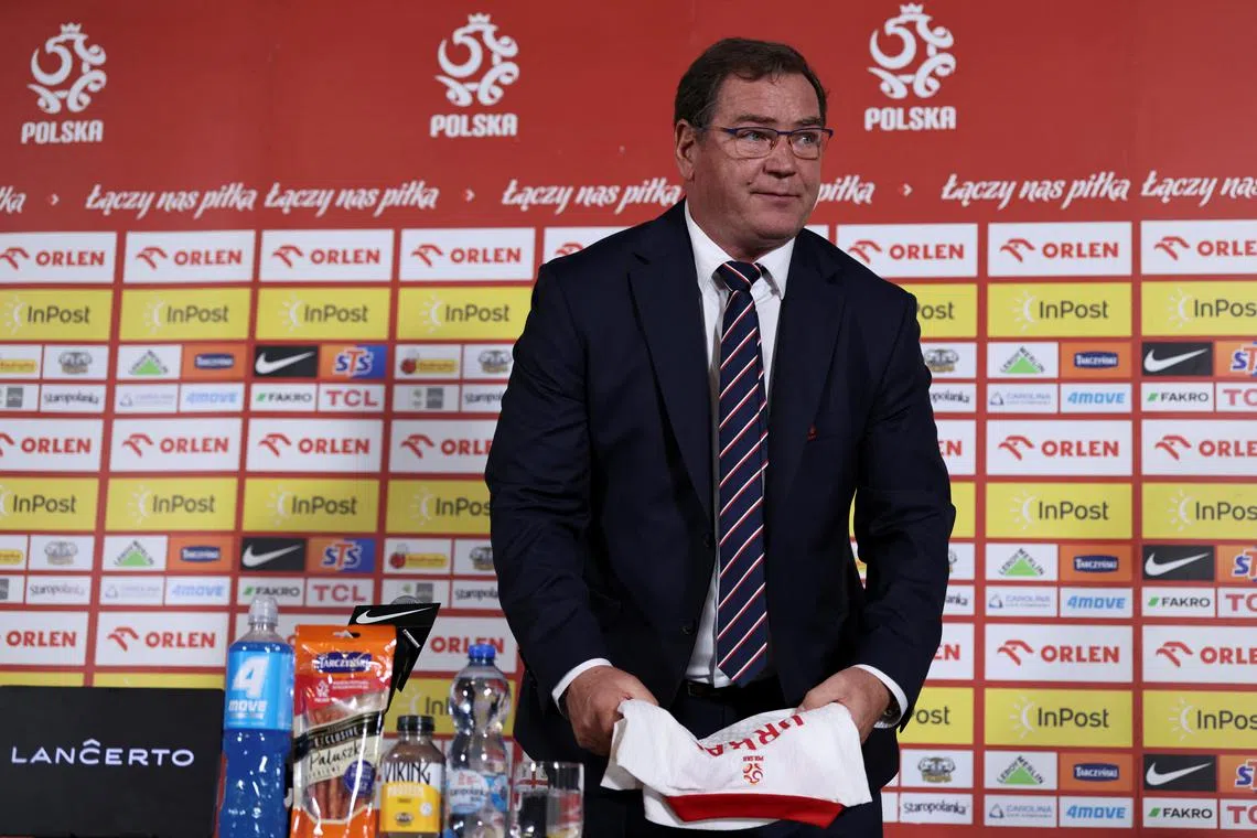 Jan Urban, newly appointed head coach of Poland's national football team, holds a team jersey during a press conference in Warsaw on July 17, 2025.