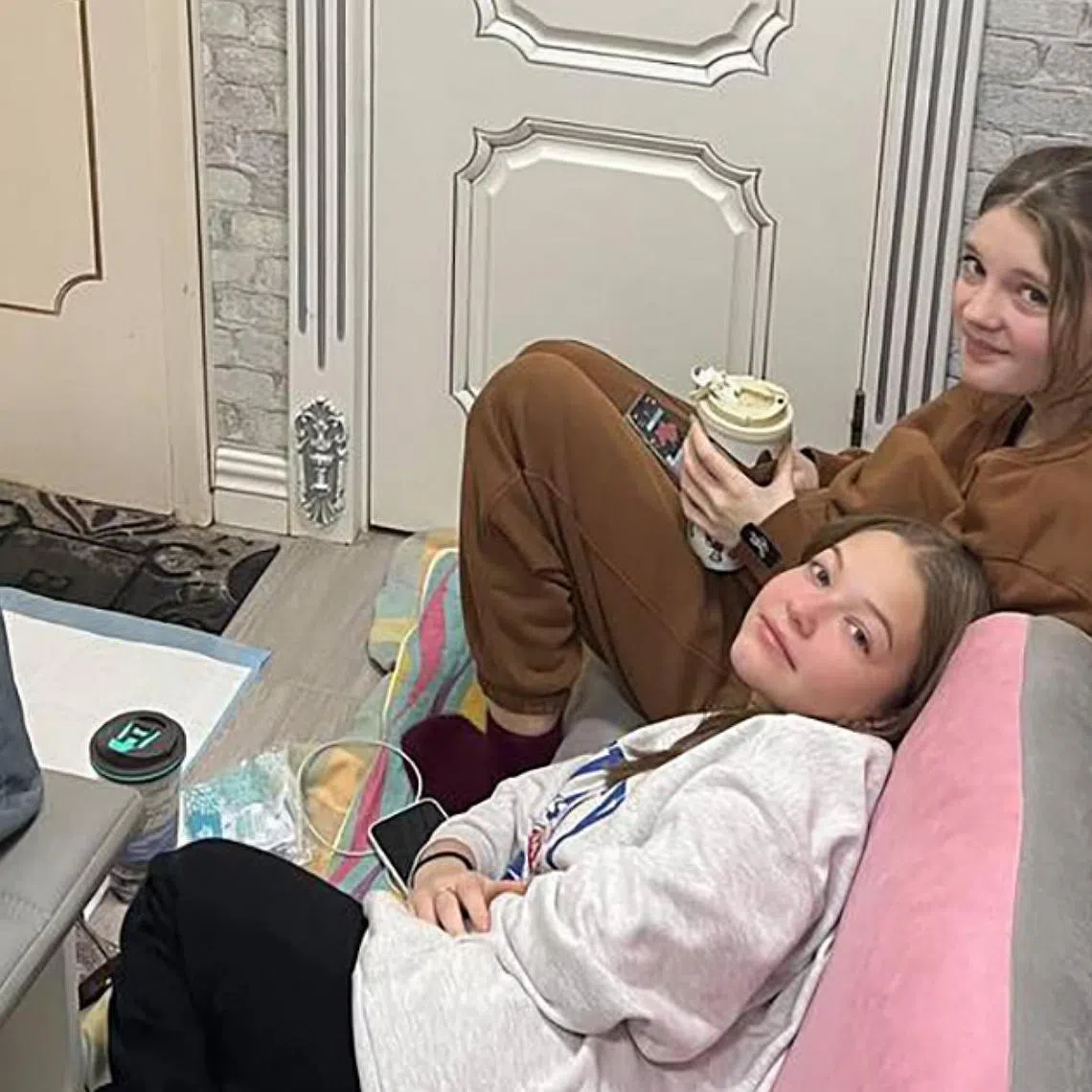 Kira Meshcherska (top) and her stepsister Daria Tkachenko now often bunk down along the windowless corridor of their home in case of missiles at night