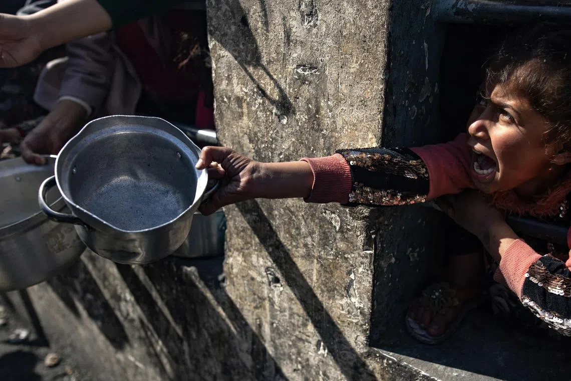epa11756145 A displaced Palestinian child holds up an empty pot as she and others wait to receive food aid provided by a Palestinian youth group in a refugee camp in Rafah, southern Gaza Strip, 25 January 2024.  EPA-EFE/HAITHAM IMAD
