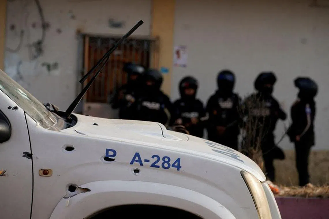FILE PHOTO: Police officers stand guard near a bullet-riddled police car at a crime scene where colleagues were killed in response to prisoner transfers from overcrowded prisons, prompting President Guillermo Lasso to declare a state of emergency in two provinces, in Guayaquil, Ecuador November 1, 2022. REUTERS/Santiago Arcos/File Photo