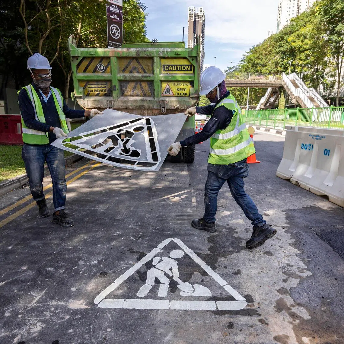 ST20250923_202505400438/esroad24/Brian Teo/Esther Loi/*EMBARGO UNTIL SEPT 24, 12AM* Workers removing the stencil for the interim reinstatement marking at a road work site along River Valley Road on Sept 23, 2025. The marking is part of a new trial by the Land Transport Authority (LTA), alerting motorists that they are driving on a temporary surface rather than the road’s permanent state. ST PHOTO: BRIAN TEO