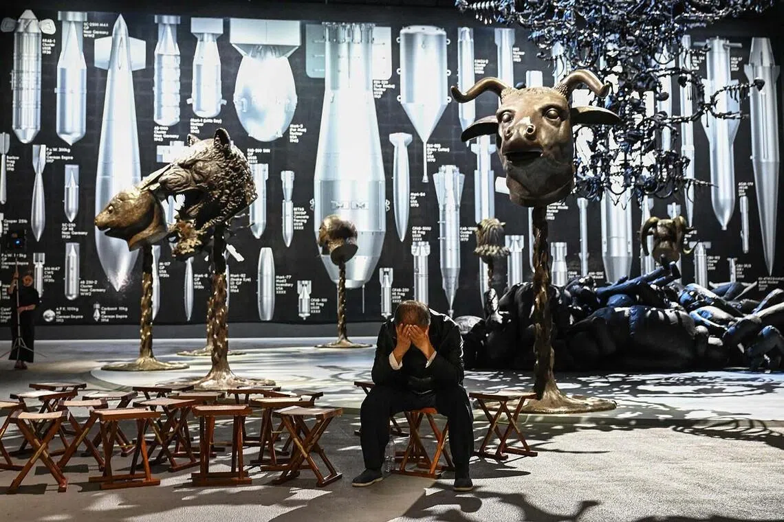 TOPSHOT - Chinese artist Ai Weiwei poses with one of his new works entitled 'History of Bombs', during a photocall to promote his forthcoming exhibition 'Ai Weiwei: Button Up!', at the Aviva Studios in Manchester, northern England, on July 1, 2026. (Photo by Peter POWELL / AFP) / RESTRICTED TO EDITORIAL USE - MANDATORY MENTION OF THE ARTIST UPON PUBLICATION - TO ILLUSTRATE THE EVENT AS SPECIFIED IN THE CAPTION