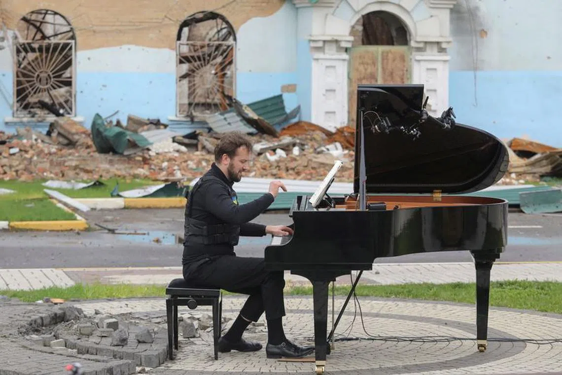 FILE PHOTO: Lithuanian musician Darius Mazintas plays a piano in front of the Central House of Culture destroyed during Russia's invasion, in the town of Irpin, outside Kyiv, Ukraine April 26, 2022.  REUTERS/Mykola Tymchenko/File Photo