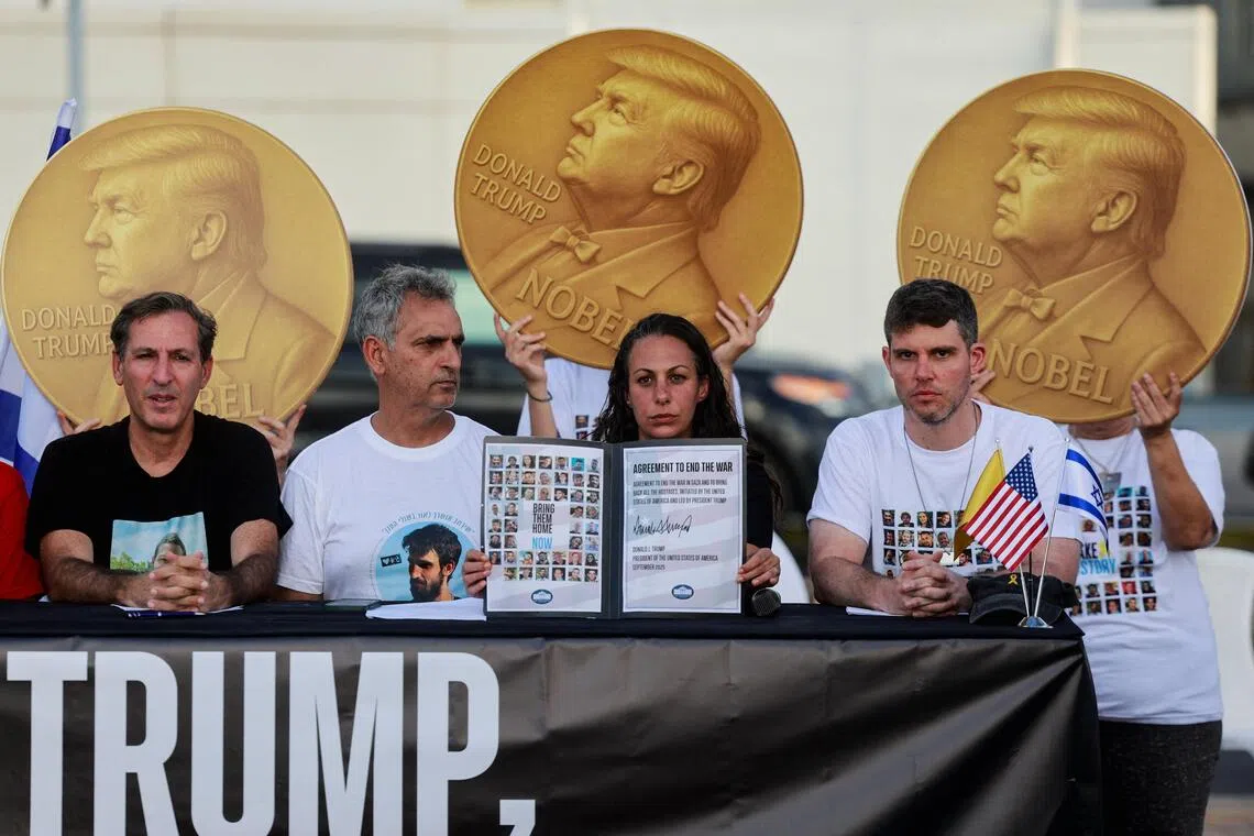 Relatives of hostages still being held in Gaza hold a news conference in front of images of US President Donald Trump and the word “Nobel” written on them.
