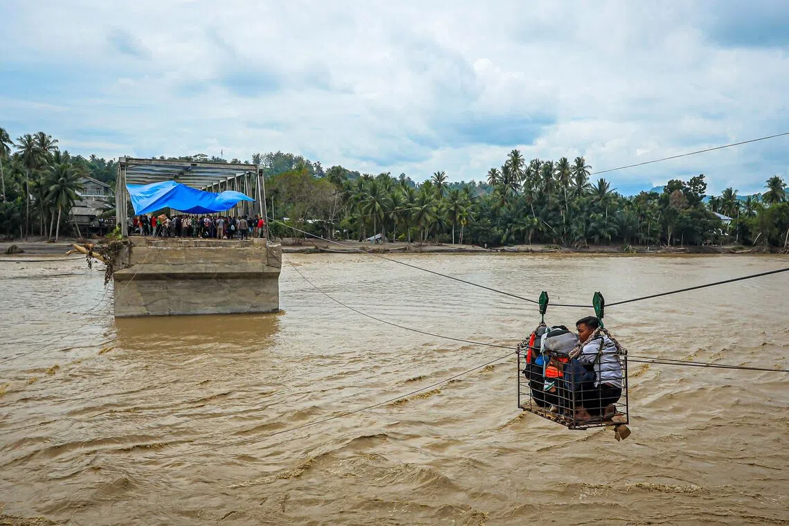 Villagers using a makeshift cable car to cross the river after the bridge was destroyed by a flash flood in Bireuen, Indonesia's Aceh province, on Dec 2, 2025. 