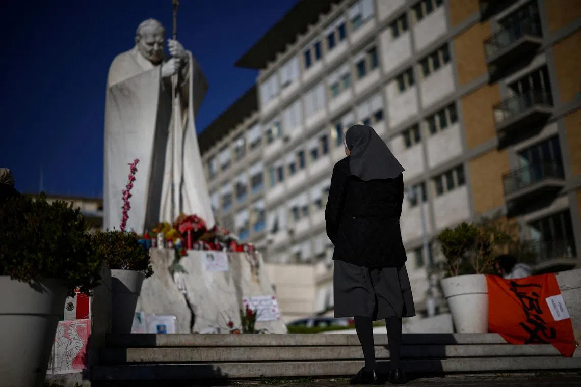A nun praying near the statue of late Pope John Paul II at the Gemelli Hospital, where Pope Francis is admitted for ongoing pneumonia treatment, in Rome, Italy, March 18, 2025. 