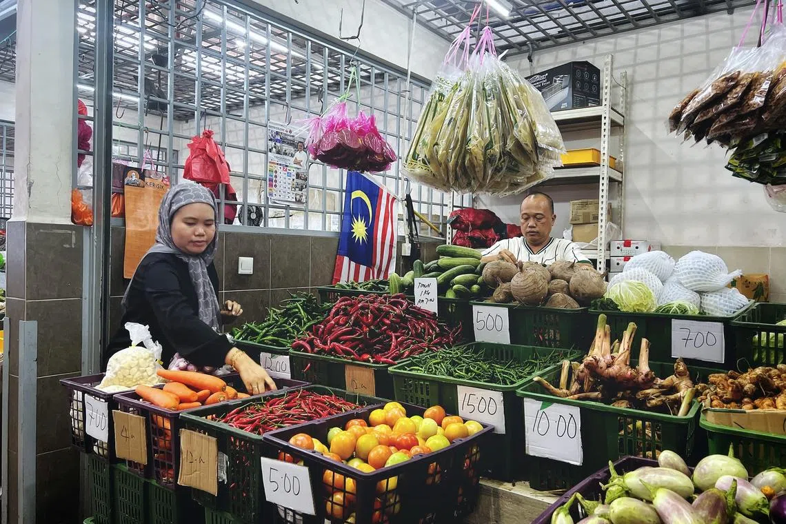 Vegetable merchant couple (from left) Athira Akma Rushdan and Wan Muhammad Hazid Haron at the Medan Niaga Kampung Melayu Majidee complex.