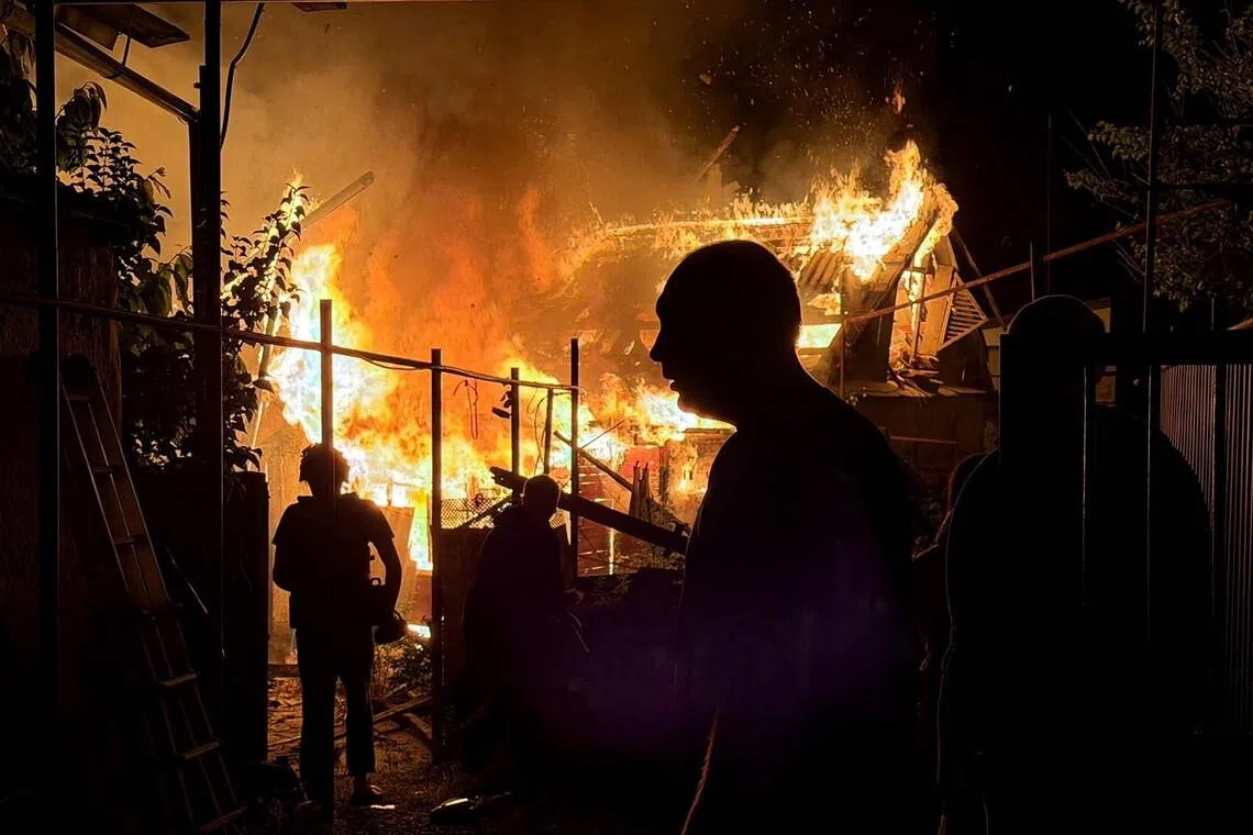 Residents looking at a private house that burns after an overnight Russian drone strike, amid Russia's attack on Ukraine, in Zaporizhzhia, Ukraine, on June 22.