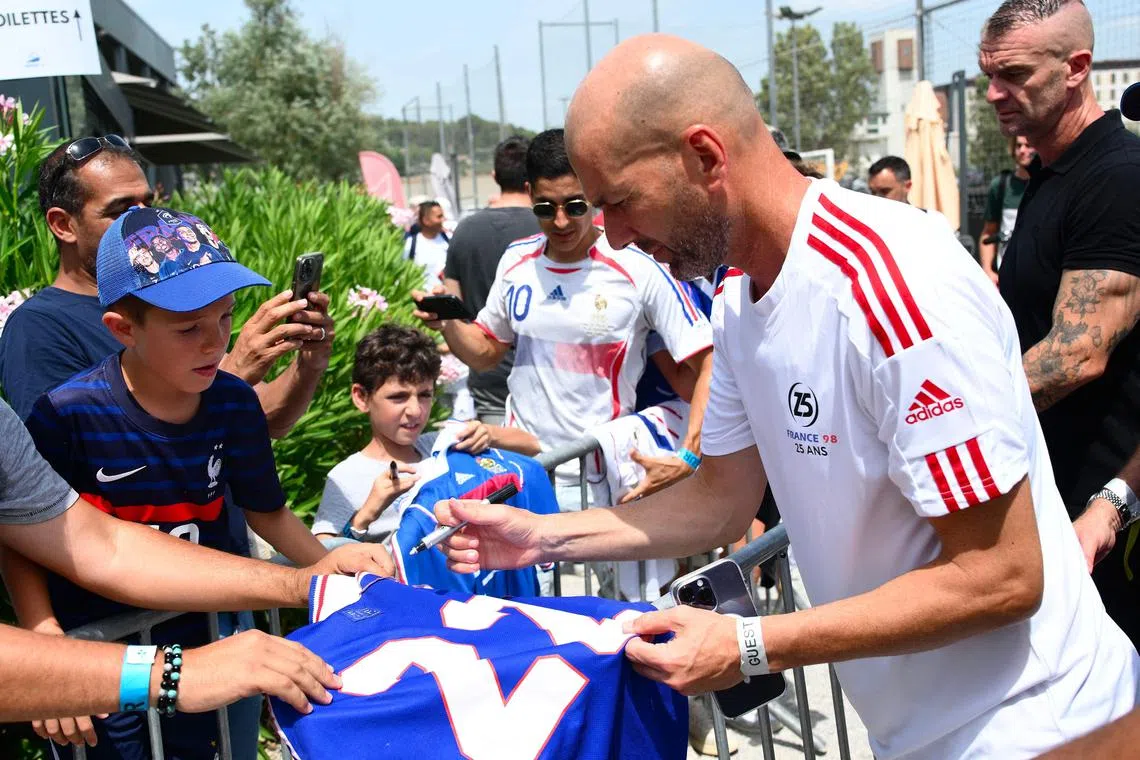 Zinedine Zidane signs autographs during the celebration of the 25th anniversary of France's 1998 World Cup victory.