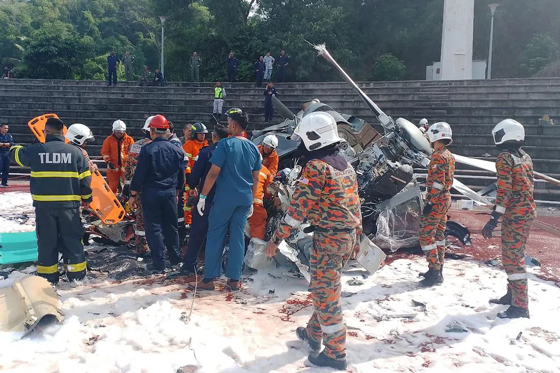 This handout picture taken and released on April 23, 2024 by Perak's Fire and Rescue Department shows rescuers inspecting the crash site after two military helicopters collided in Lumut in Malaysia's Perak state.