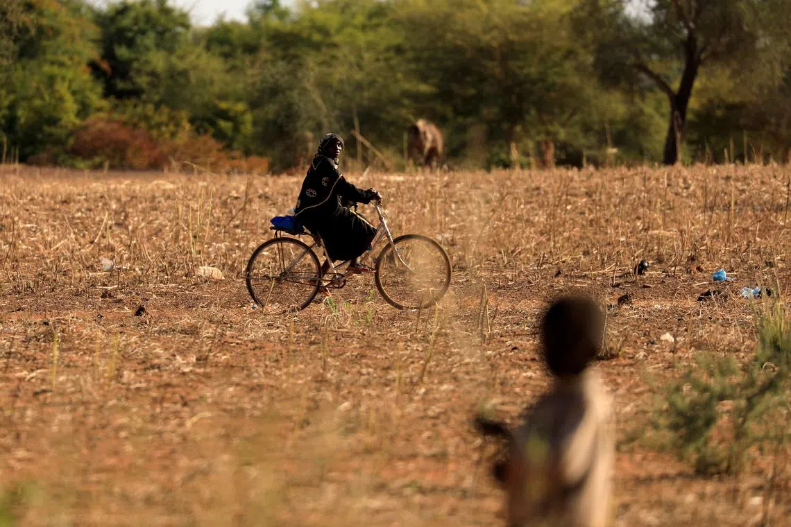 FILE PHOTO: A child who fled with his parents from attacks of armed militants in the Sahel region watches a woman on a bicycle at a camp for internally displaced people (IDPs) in Kaya, Burkina Faso November 23, 2020. Picture taken November 23, 2020. REUTERS/Zohra Bensemra/File Photo