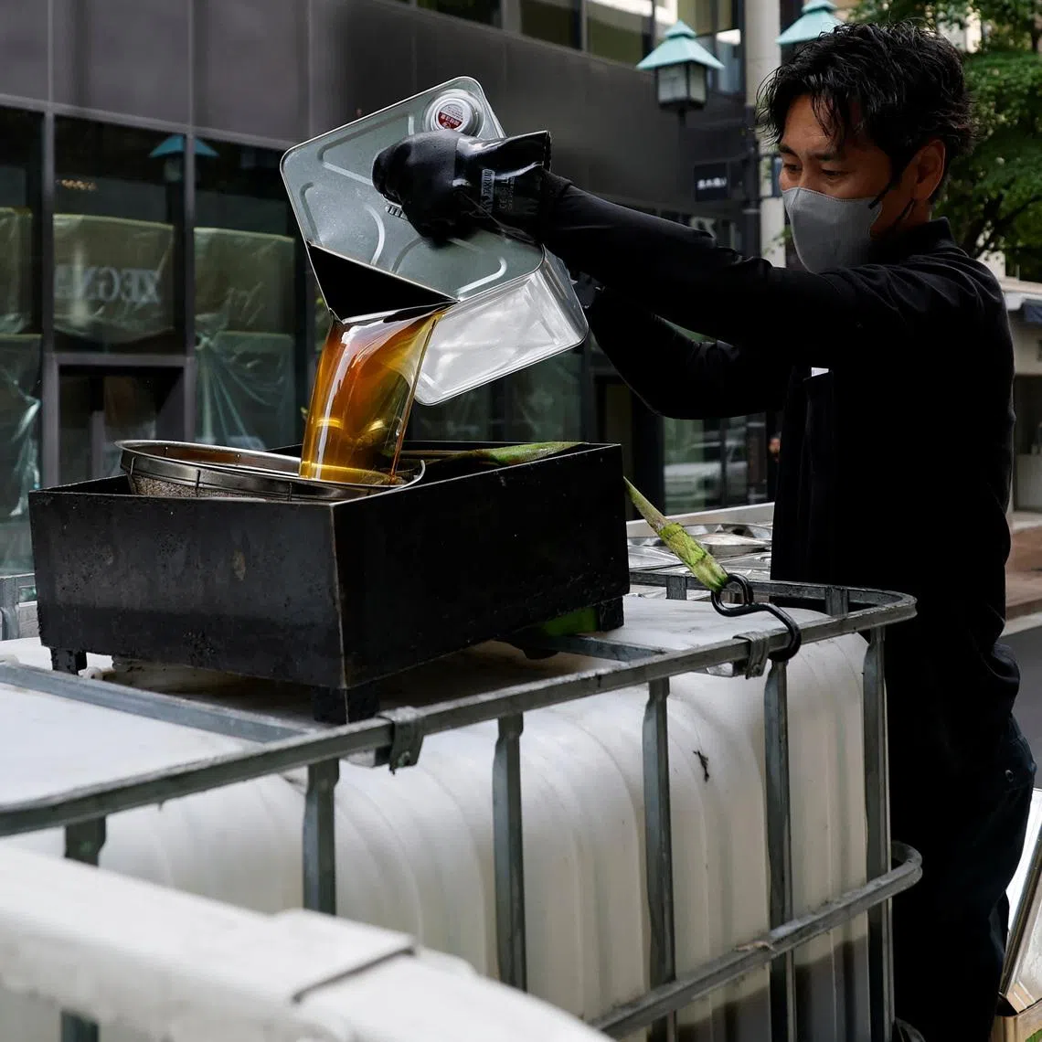 A worker from a firm collecting used cooking oil to produce sustainable aviation fuel pours oil collected from a Tempura Ten-ichi restaurant into a tank, in Tokyo on April 22.