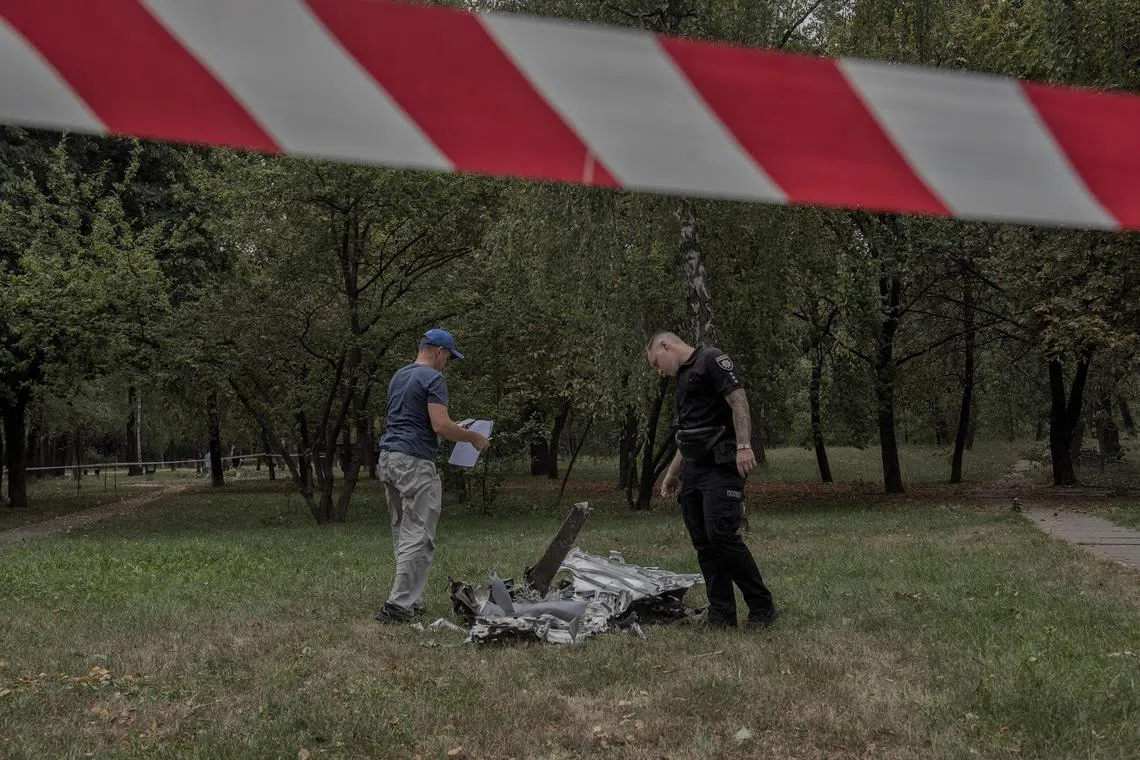 Ukrainian police officers examine fallen debris, following Russian drone and missile attacks in a residential area of Kyiv.