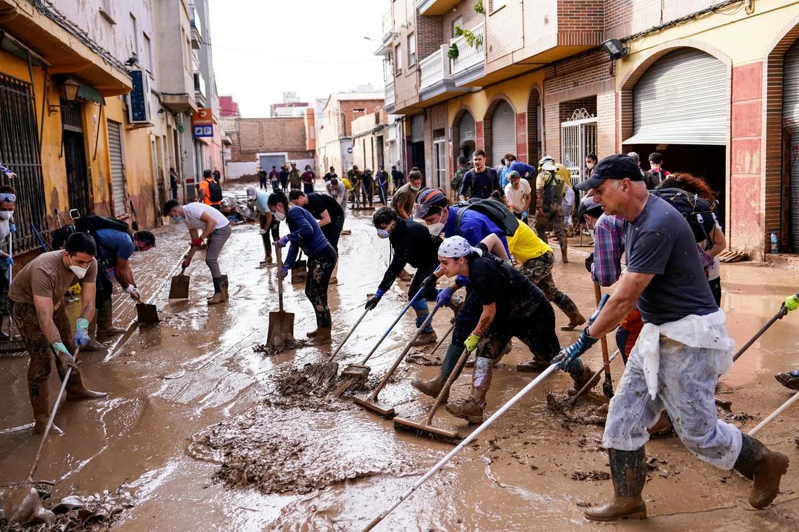 People clean a muddy street in the aftermath of the flooding caused by heavy rains in Massanassa, Valencia, Spain, November 8, 2024. REUTERS/Ana Beltran