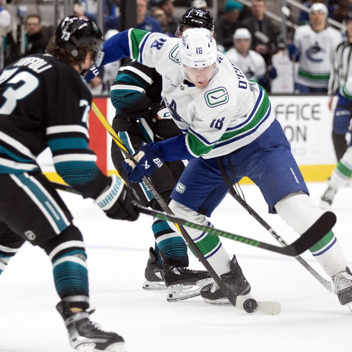 Feb 6, 2025; San Jose, California, USA; Vancouver Canucks left winger Drew O'Connor (18) tries to move the puck past San Jose Sharks center Tyler Toffoli (73) during the first period at SAP Center at San Jose. Mandatory Credit: D. Ross Cameron-Imagn Images