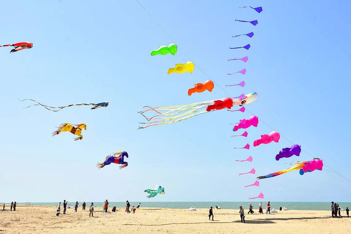 People watching and taking photos during a kite festival on Ao Manao Beach in the southern Thai province of Narathiwat on April 15, 2024. 