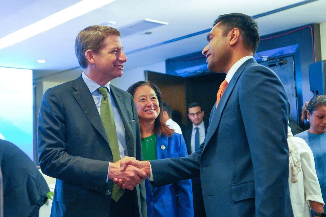Scott Nathan, CEO of International Development Finance Corp., left, and Karan Adani, managing director and CEO of Adani Ports and Special Economic Zone., right, shake hands after a news conference in Colombo, Sri Lanka.
