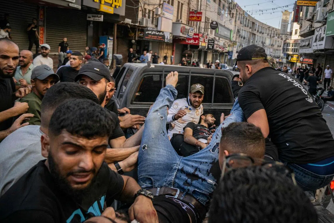 Two injured men are carried away in the back of a pick-up truck after being reportedly shot by Israeli forces during confrontations with them in the occupied West Bank city of Jenin.