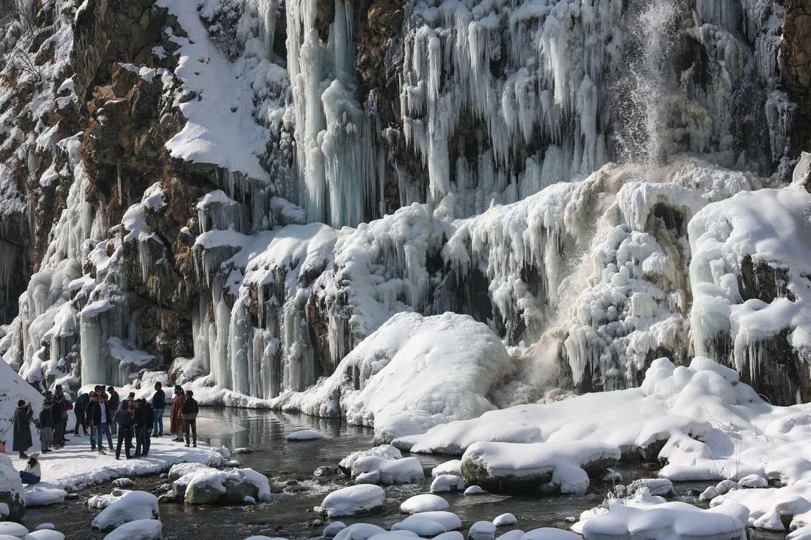 Tourists enjoy near a frozen waterfall in the Drang area of Tangmarg, north of Srinagar, the summer capital of Indian Kashmir, 16 January 2023. Tourist Station and waterfall at Drang area of Tangmarg is frozen due to a fall in temperature. Ski resort Gulmarg recorded a low of minus 12.0°C and It was the coldest night so far recorded in the region.  