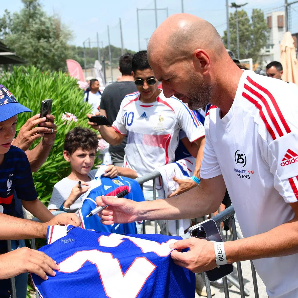 Zinedine Zidane signs autographs during the celebration of the 25th anniversary of France's 1998 World Cup victory.