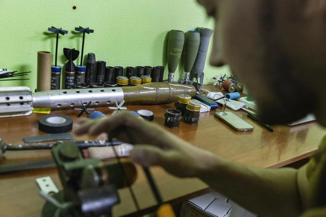 A fighter with a unit in Ukraine’s National Guard modifies grenades to be used as bombs attached to small drones, at a workshop outside Sloviansk, Ukraine.