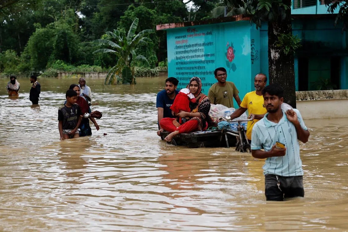 FILE PHOTO: People move a cart with a woman and child through a flooded street, in the Fazilpur area of Feni, Bangladesh, August 26, 2024. REUTERS/Mohammad Ponir Hossain/File Photo