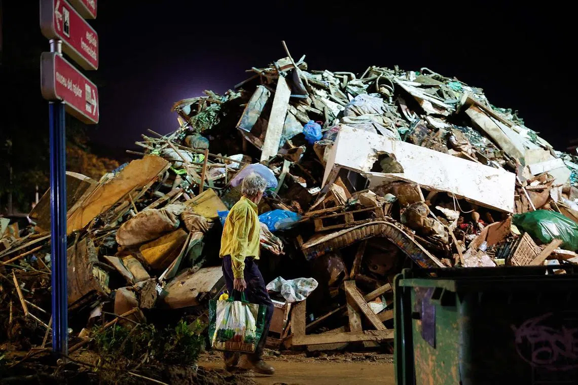 A person walks next to mud-covered debris following heavy rains that caused floods, in Paiporta, near Valencia, Spain, November 4, 2024. REUTERS/Eva Manez TPX IMAGES OF THE DAY