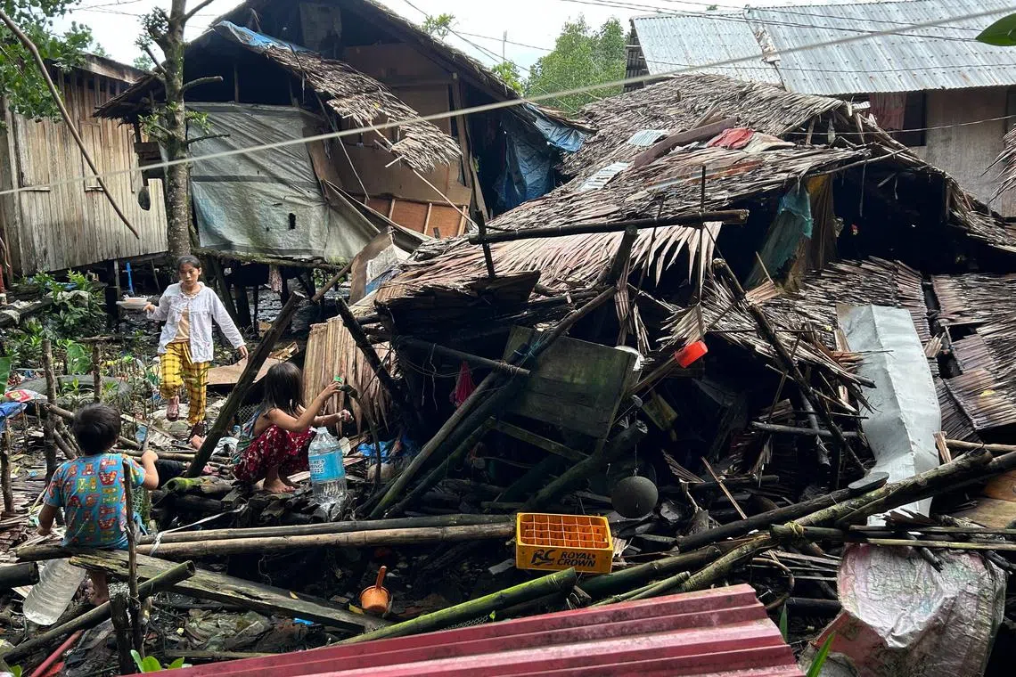 Residents fetch water next to a destroyed house in Hinatuan, Surigao del Sur province.