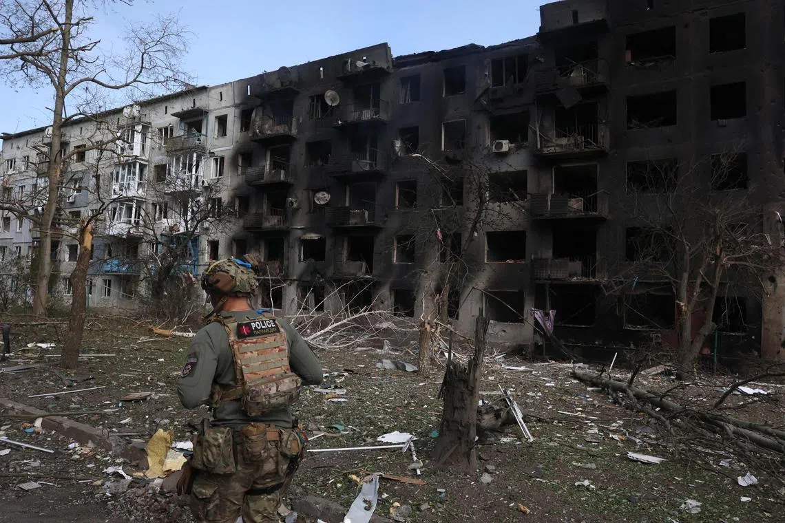 A Ukainian police officer walking past a destroyed residential building in the village of Ocheretyne, near the town of Avdiivka, in the Donetsk region of Ukraine, on April 15, 2024.