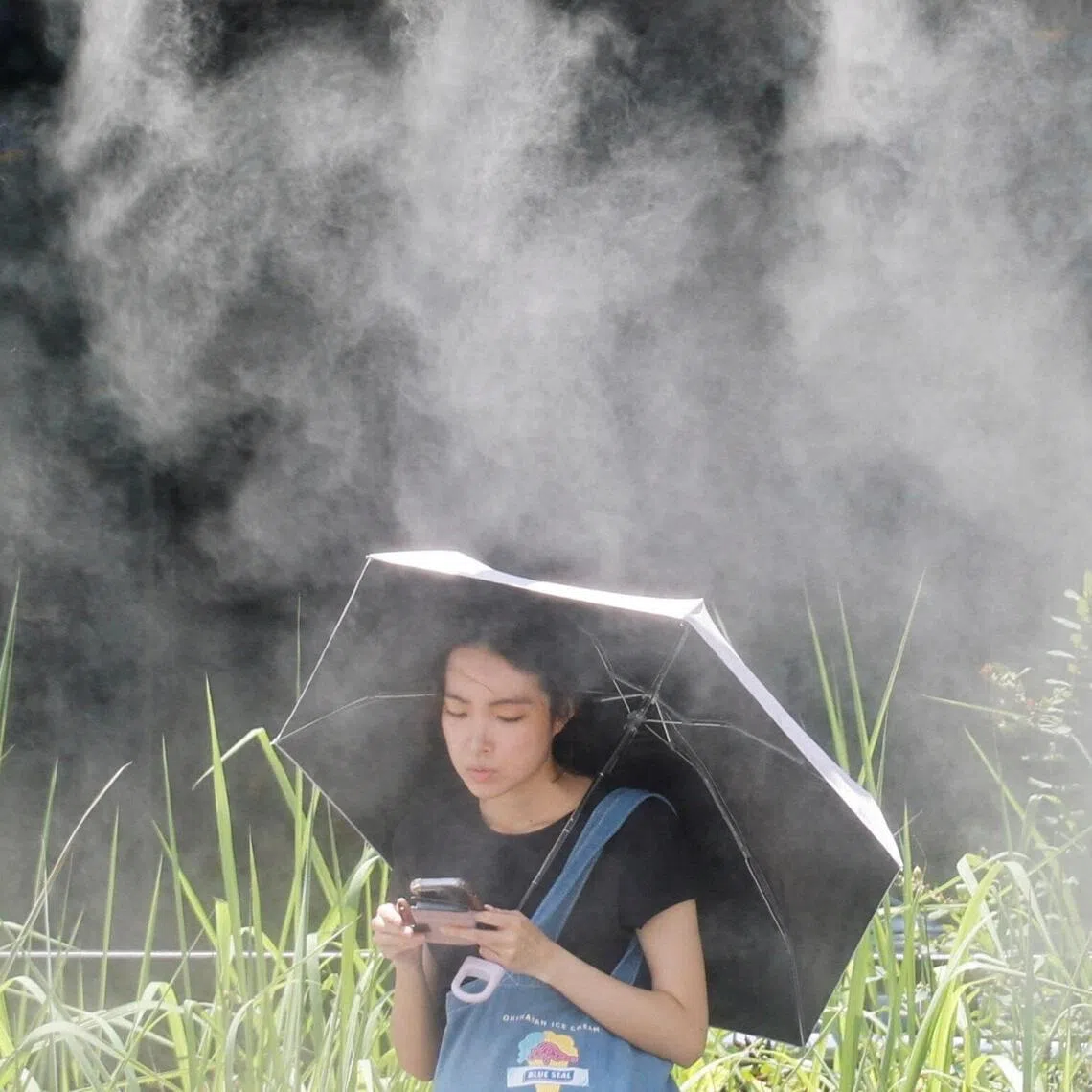 A woman takes a break under a cooling mist during a heatwave in Tokyo on July 15.
