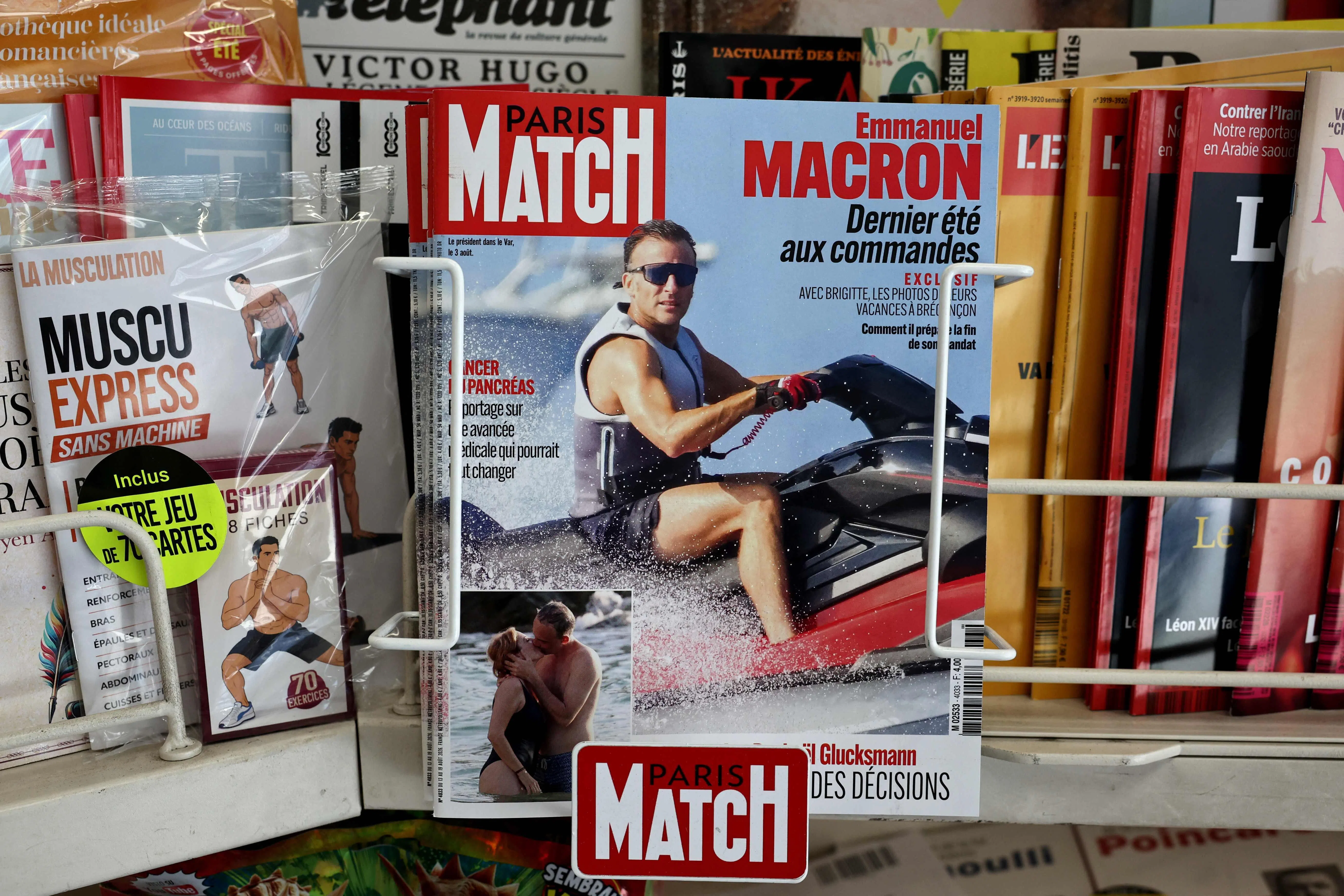 This photograph taken in Paris on August 14, 2026 shows the cover of French magazine "Paris Match" depicting France's President Emmanuel Macron on a jet ski during his holiday near the Presidential residence in Bregancon, south-eastern France. Emmanuel Macron is facing a new trial for being out of touch, criticised over a Paris Match feature in which he is photographed enjoying various water activities, including jet skiing, in the middle of a summer marked for the French by successive heatwaves and wildfires. (Photo by SIMON WOHLFAHRT / AFP)