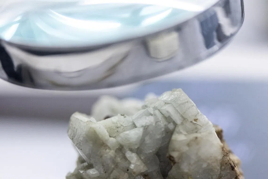 A sample of monazite, a mineral used in the rare earth industry to extract elements such as cerium, lanthanum, and neodymium, is displayed next to a magnification glass at the Geological Museum of China in Beijing on Oct 14, 2025. 