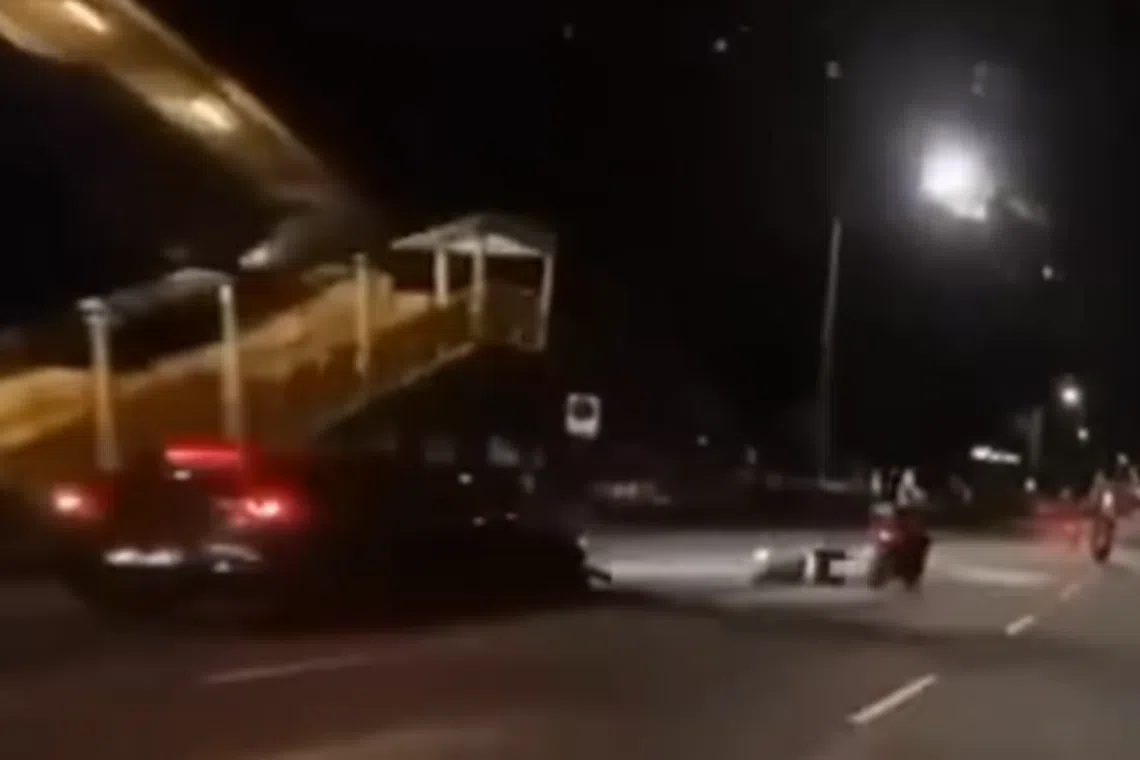 The car collides with the rear of a motorcycle in the left-most lane and the rider is flung off his bike before landing on the road.