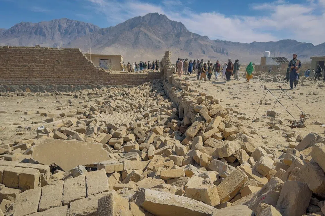 People stand near a house damaged in what the Taliban said was a Pakistani air strike on the outskirts of Kabul, Afghanistan, March 13, 2026. Picture taken with a mobile phone. REUTERS/Sayed Hassib