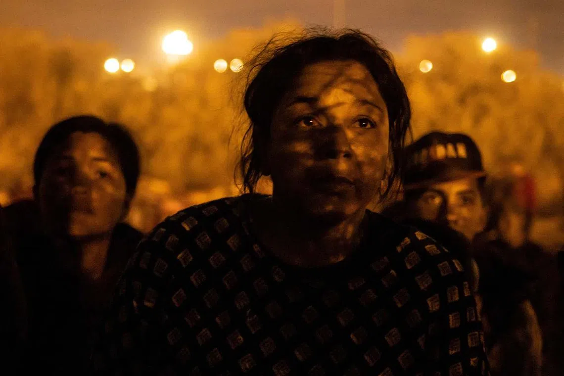 The shadow of razor wire falling on the face of Alejandra, 32, of Venezuela, as she and others prepare to breach a fence line into the United States from the bank of the Rio Grande River, in El Paso, Texas, US, April 2, 2024. 