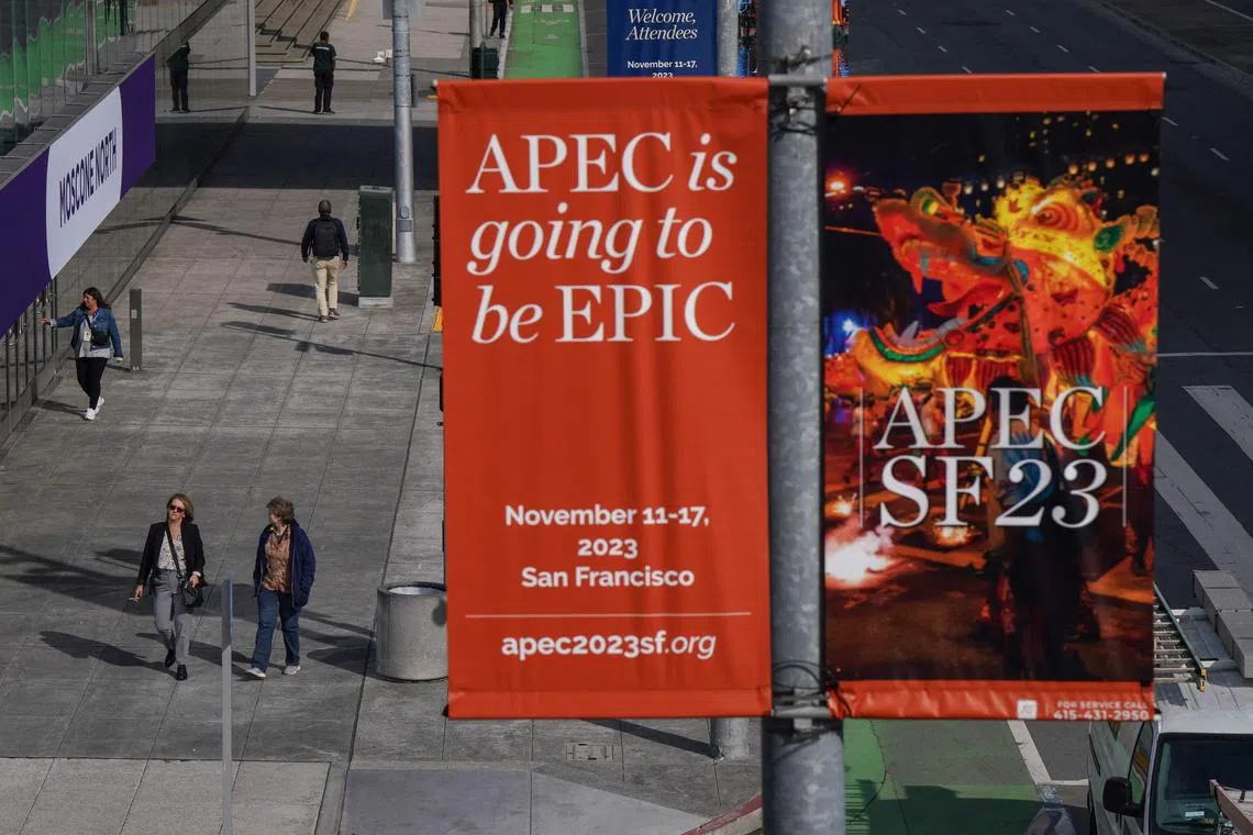 People walk under signage advertising the Asia-Pacific Economic Cooperation (APEC) meetings ahead of the summit at the Moscone Center in San Francisco, California, on November 9, 2023. (Photo by Loren Elliott / AFP)