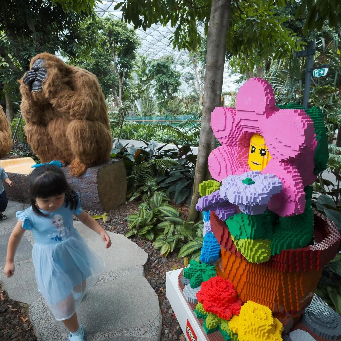 A giant LEGO minifigure made of LEGO bricks amid a topiary display at Jewel Changi Airport’s Canopy Park on May 26, 2026.