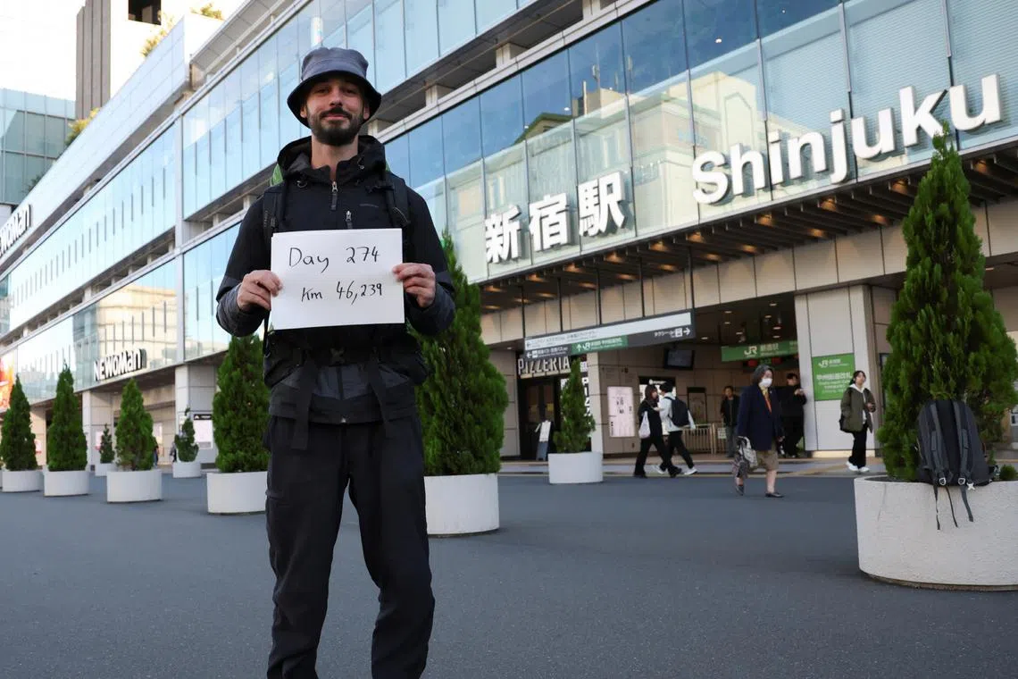 Mr Omar Nok, 30, an Egyptian who travelled from Cairo to Tokyo, holding a sign noting the days and distance he has travelled, in front of Shinjuku station in Tokyo on Nov 7.
