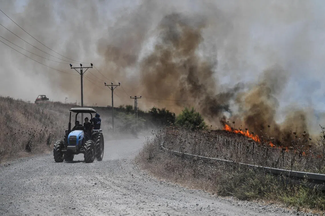 Fires blaze near a road, after Lebanon's Hezbollah said it launched more than 200 rockets and a swarm of drones at Israeli military sites, in Golan Heights on July 4.