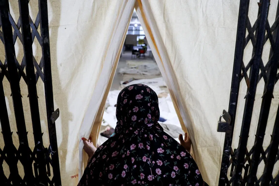 A woman looks towards the bodies of the victims of a bus accident at a mortuary in Bangladesh.