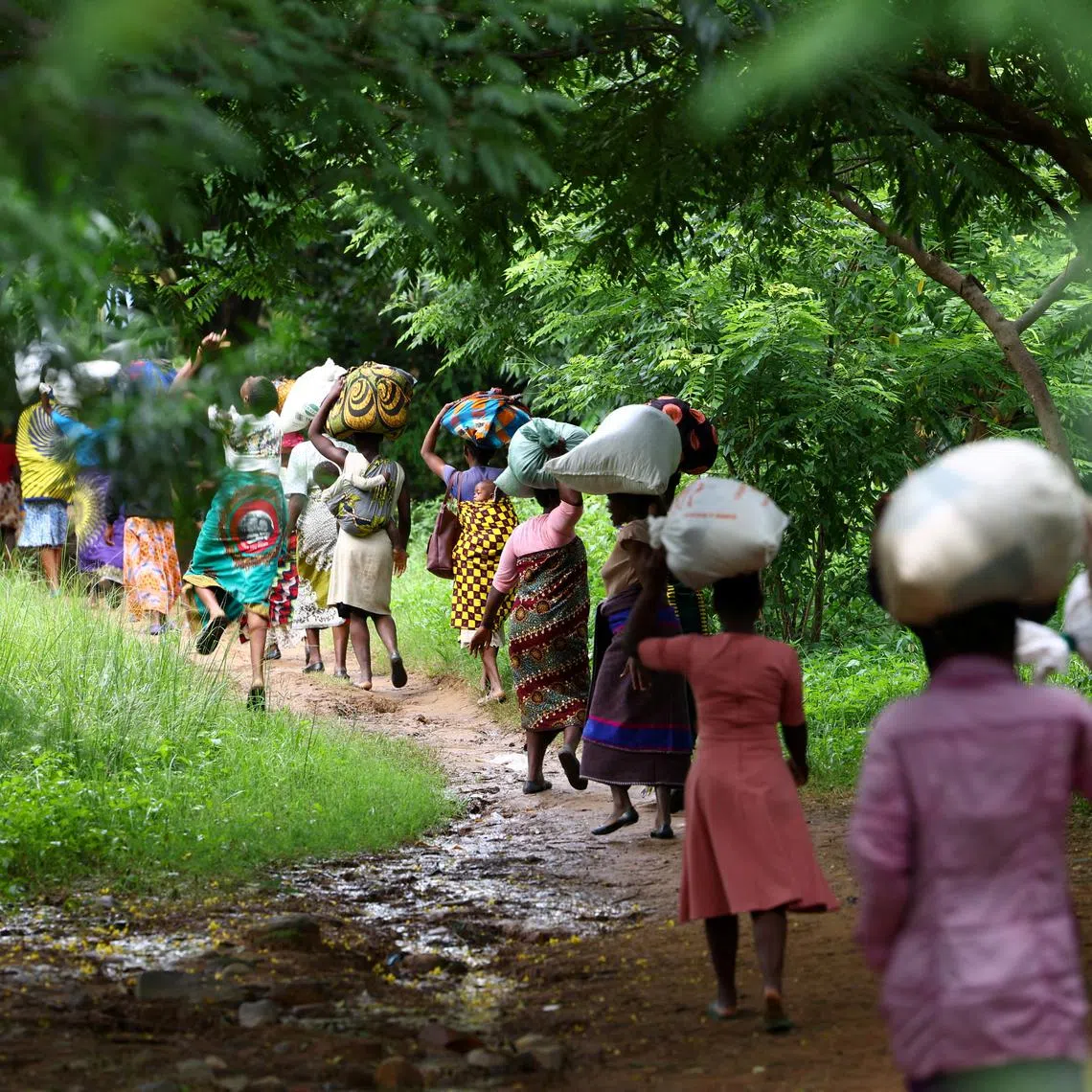 FILE PHOTO: Flood victims from Mtauchira village carry food they received from the Malawi government in the aftermath of Cyclone Freddy that destroyed their homes in Blantyre, Malawi, March 16, 2023. REUTERS/Esa Alexander/File Photo
