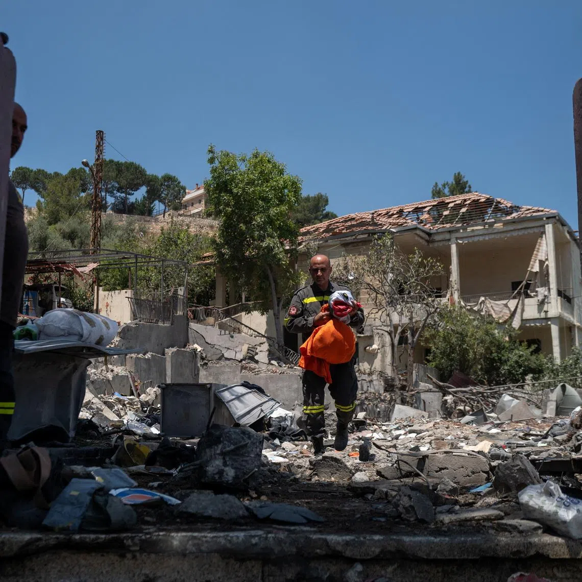 A member of the government-run Lebanese Civil Defense, the country's primary firefighting, first aid, and rescue force, holds a national flag and personal belongings salvaged from the rubble while inspecting their headquarters in Nabatieh, Lebanon, June 17, 2026, following the deal between the United States and Iran. The headquarters was destroyed in an Israeli airstrike in May. REUTERS/Zohra Bensemra