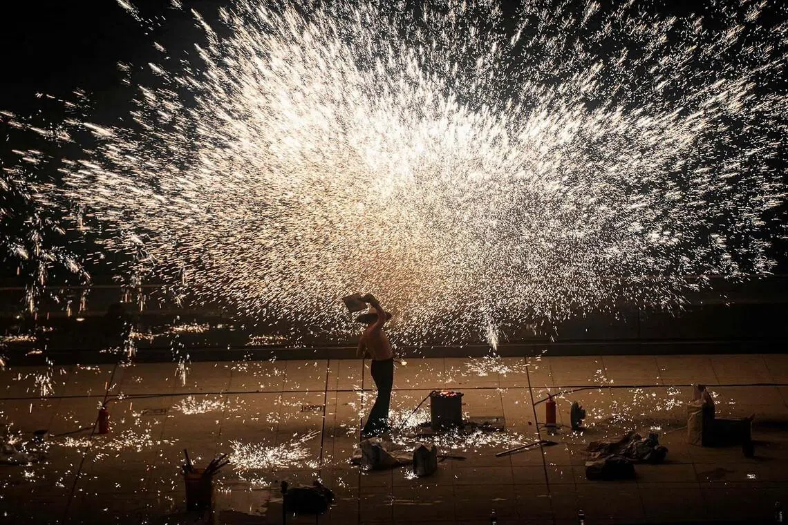 A performer throwing molten iron to create sparks during a performance on the Bund promenade along the Huangpu river, ahead of the upcoming Lunar New Year of the Horse in Shanghai on Feb 2, 2026. 