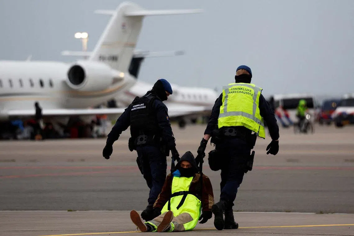 Police officers detain a climate activist during a protest against environmental pollution from aviation, at Amsterdam's Schiphol Airport, in Schiphol, Netherlands Nov 5, 2022. 