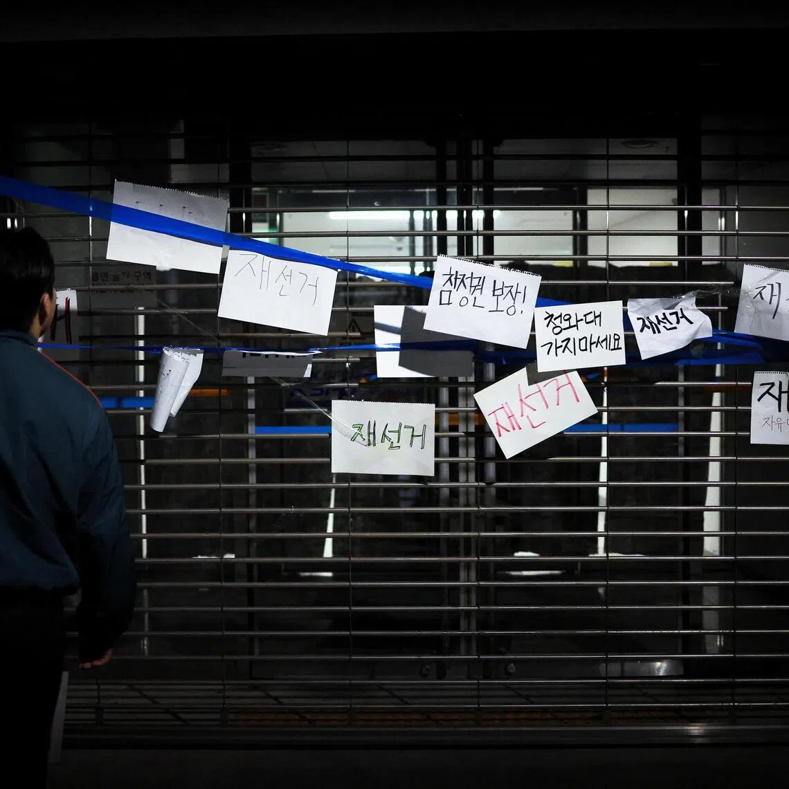 Signs reading ‘Rerun the election’ and ‘Guarantee voting rights’ are sticked onto a gate as people surround a vote-counting centre to protest, in Seoul, South Korea, on June 6.