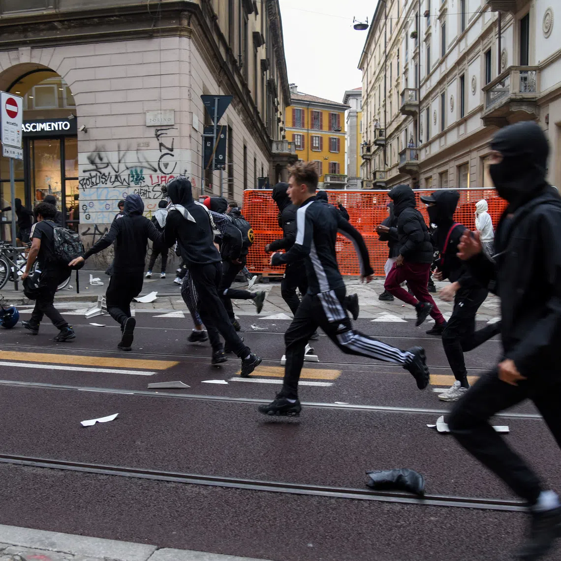 Protesters run along a street strewn with debris during a protest over the state of public services and the rising cost of living in Milan, Italy, on Oct 18.