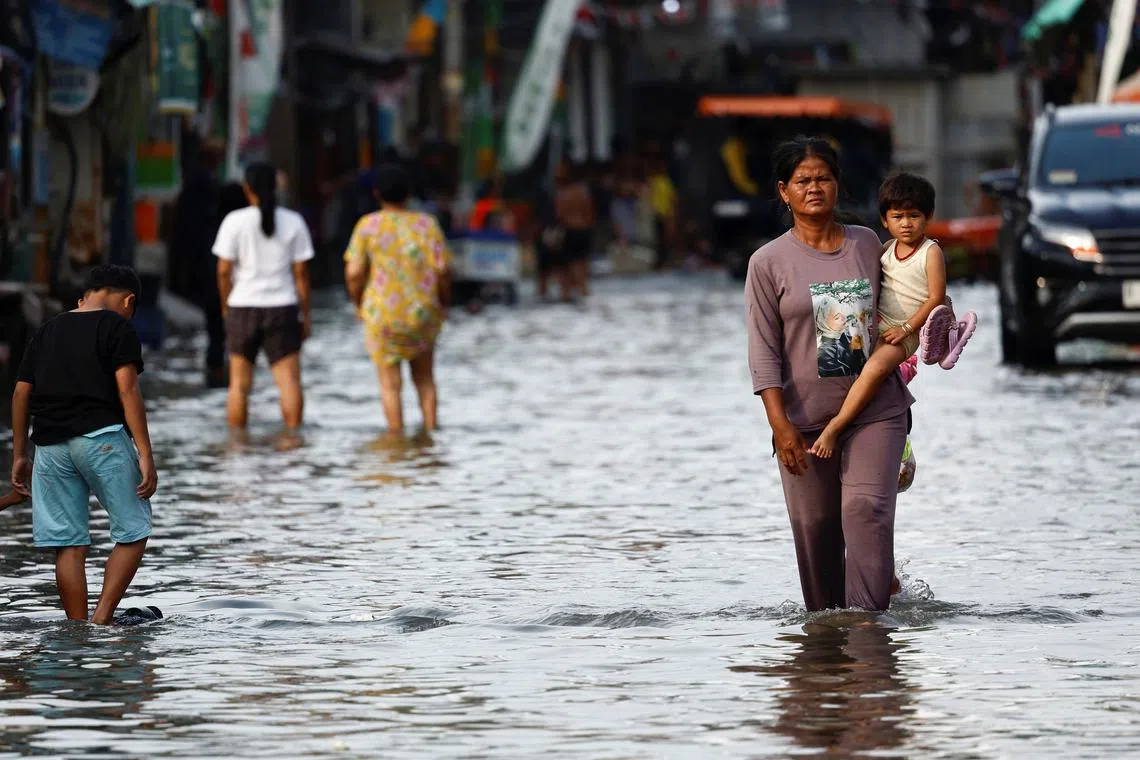 FILE PHOTO: People walk through water at a flooded area affected by rising sea levels and land subsidence in North Jakarta, Indonesia, November 20, 2024. REUTERS/Willy Kurniawan/File Photo