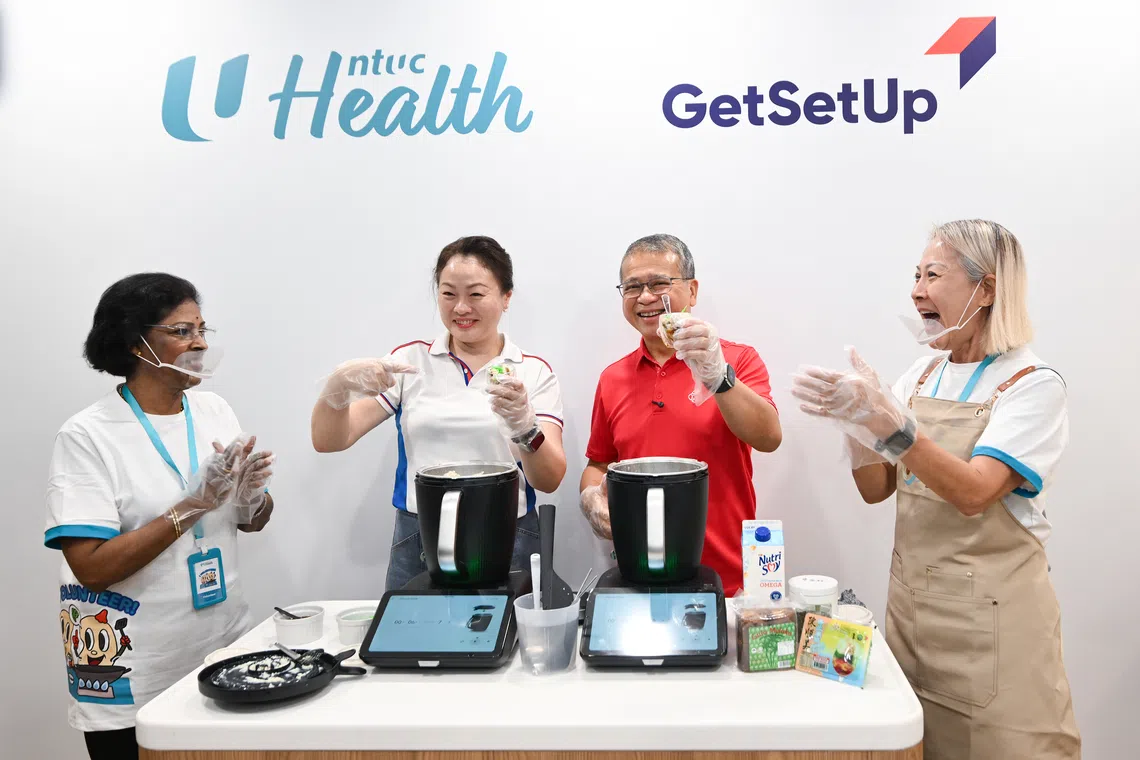 Marine Parade-Braddell Heights GRC MP Diana Pang (left) and  Law Minister Edwin Tong (right) during a livestream, teaching a healthy chendol recipe, at the opening of an NTUC Health Active Ageing Centre.