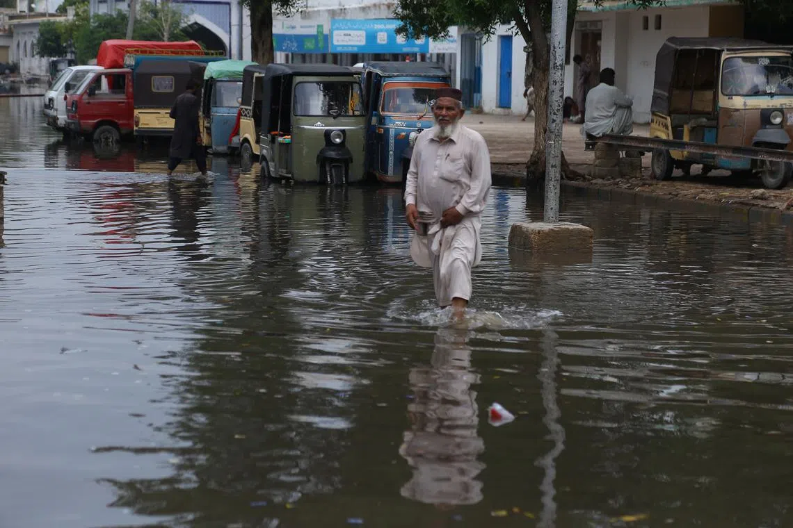 A man wades through floodwaters after torrential rain in Hyderabad, Pakistan, on Aug 20.